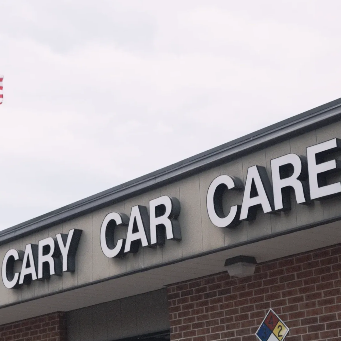 Sign for Cary Car Care on building facade with brickwork.
