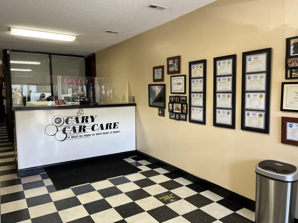 Interior of Cary Car-Care: Reception area with black and white checkered floor, framed certificates, and a front desk.