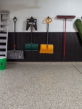A garage with snow shovels hanging on the wall.