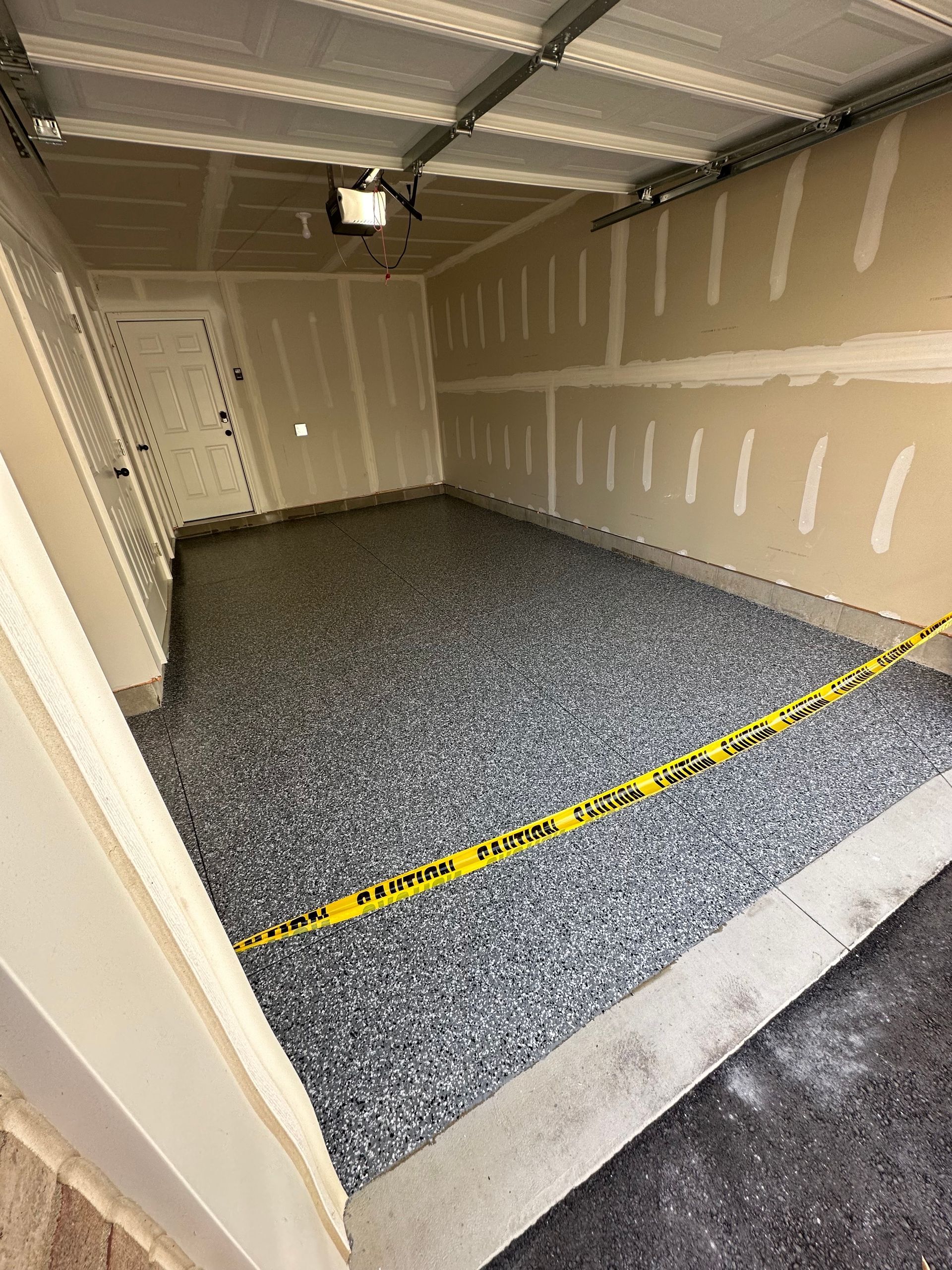 A garage with a concrete floor and a yellow tape.