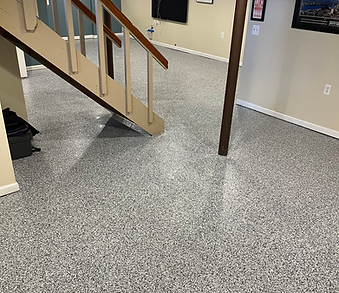 A basement with a staircase and a gray floor.