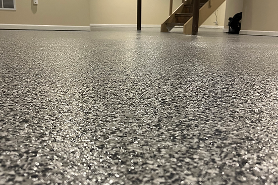 A close up of a garage floor with a staircase in the background.