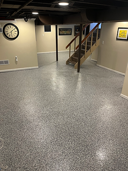 A basement with a clock on the wall and stairs.