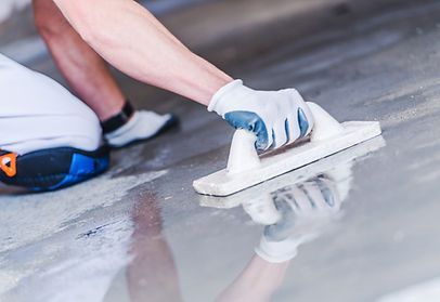A person is using a trowel on a concrete floor.
