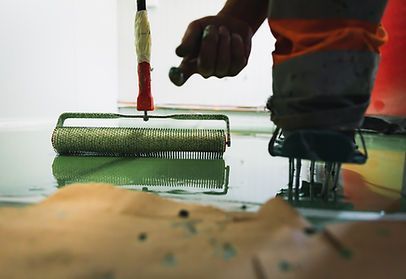A person is painting a floor with a roller.