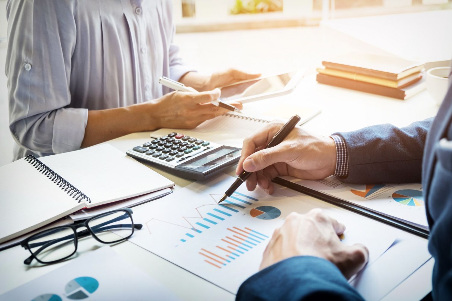 People reviewing financial charts and calculator at a bright desk