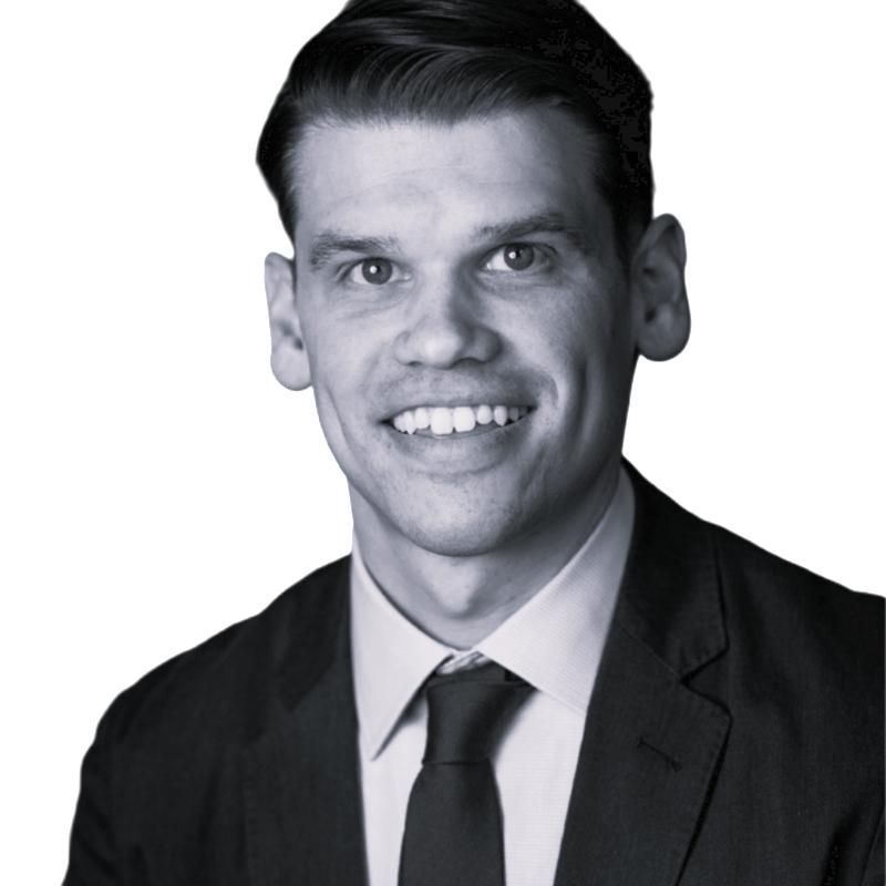 Black-and-white headshot of a man in a suit and tie, smiling at the camera.