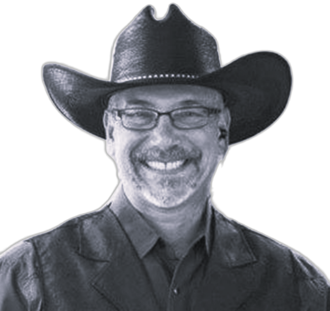 Smiling man wearing glasses and a black cowboy hat, posed against a plain background