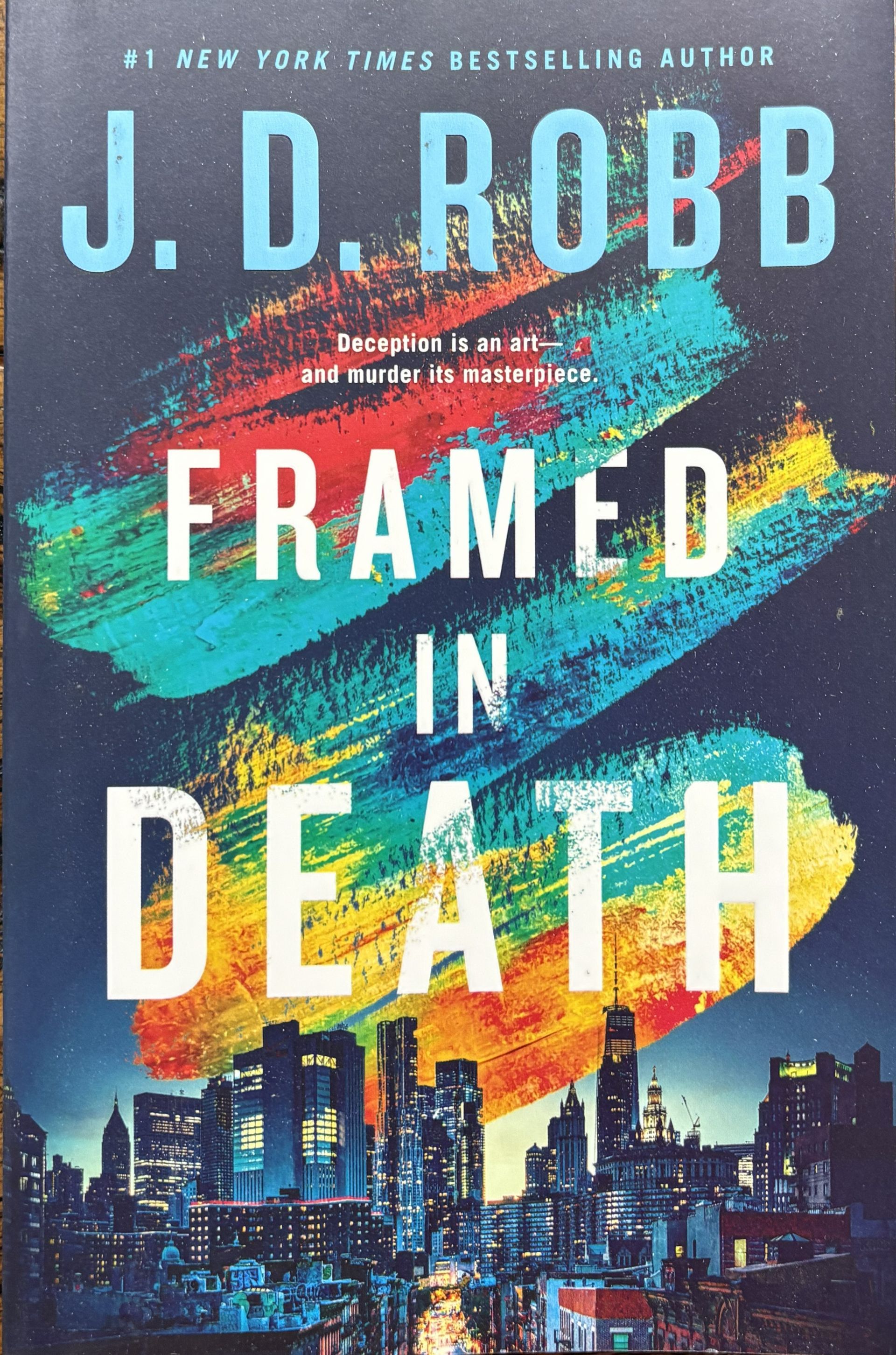 Book Title: "Framed in Death" by  by J.D. Robb. Cover displays a skyline at bottom.