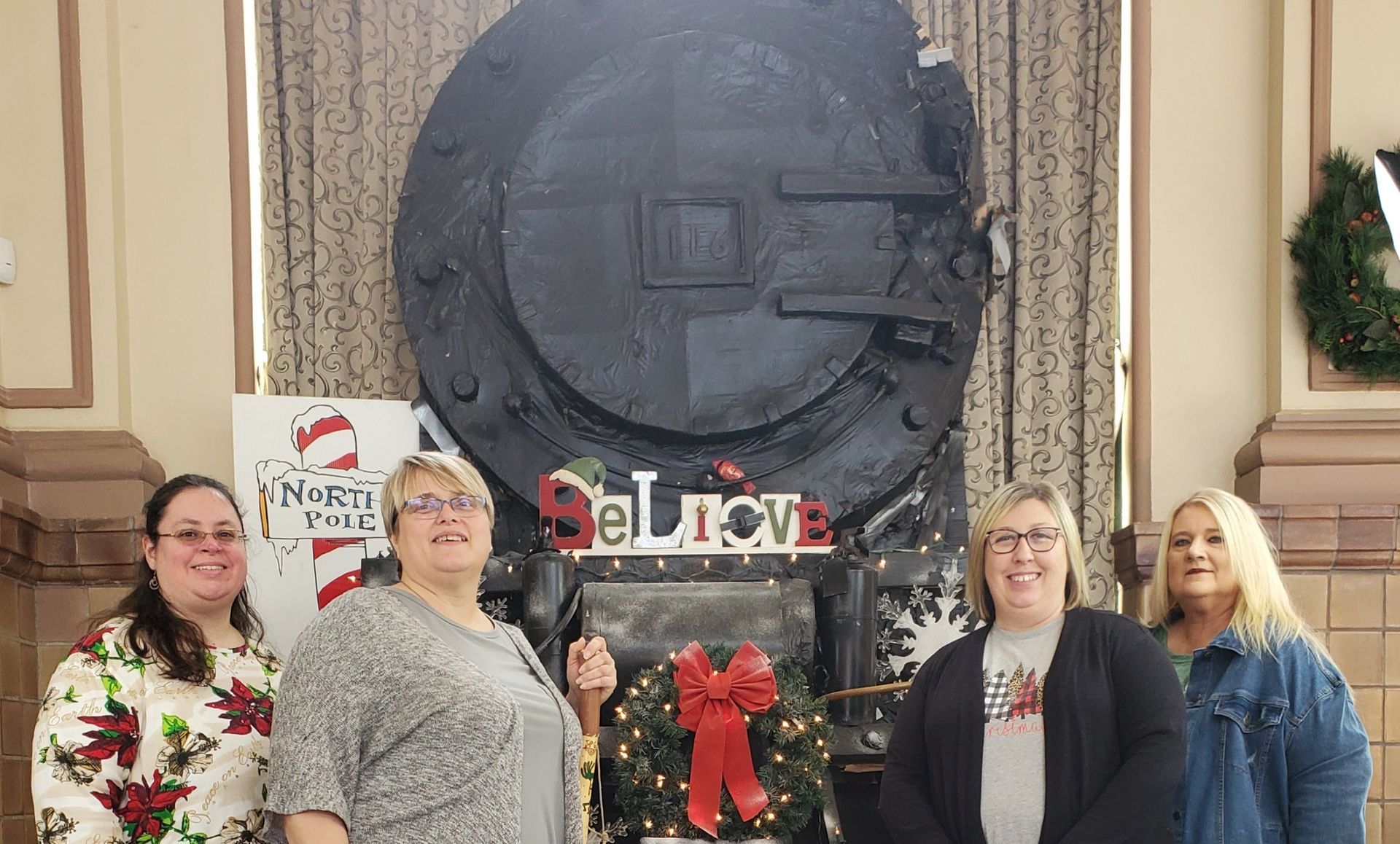 Four women pose in front of a train engine display with a 