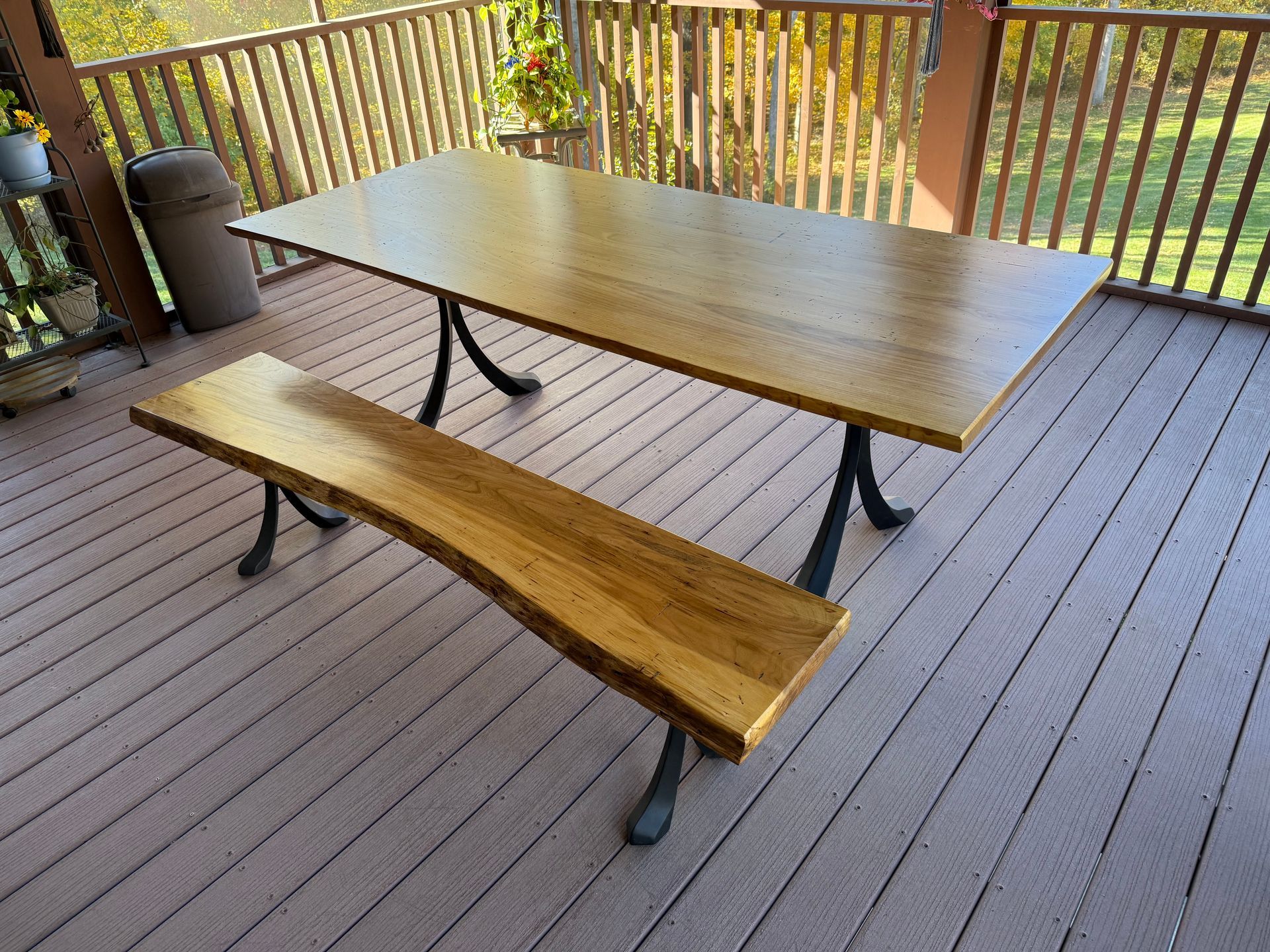 Wooden dining table and bench on a deck with metal legs.