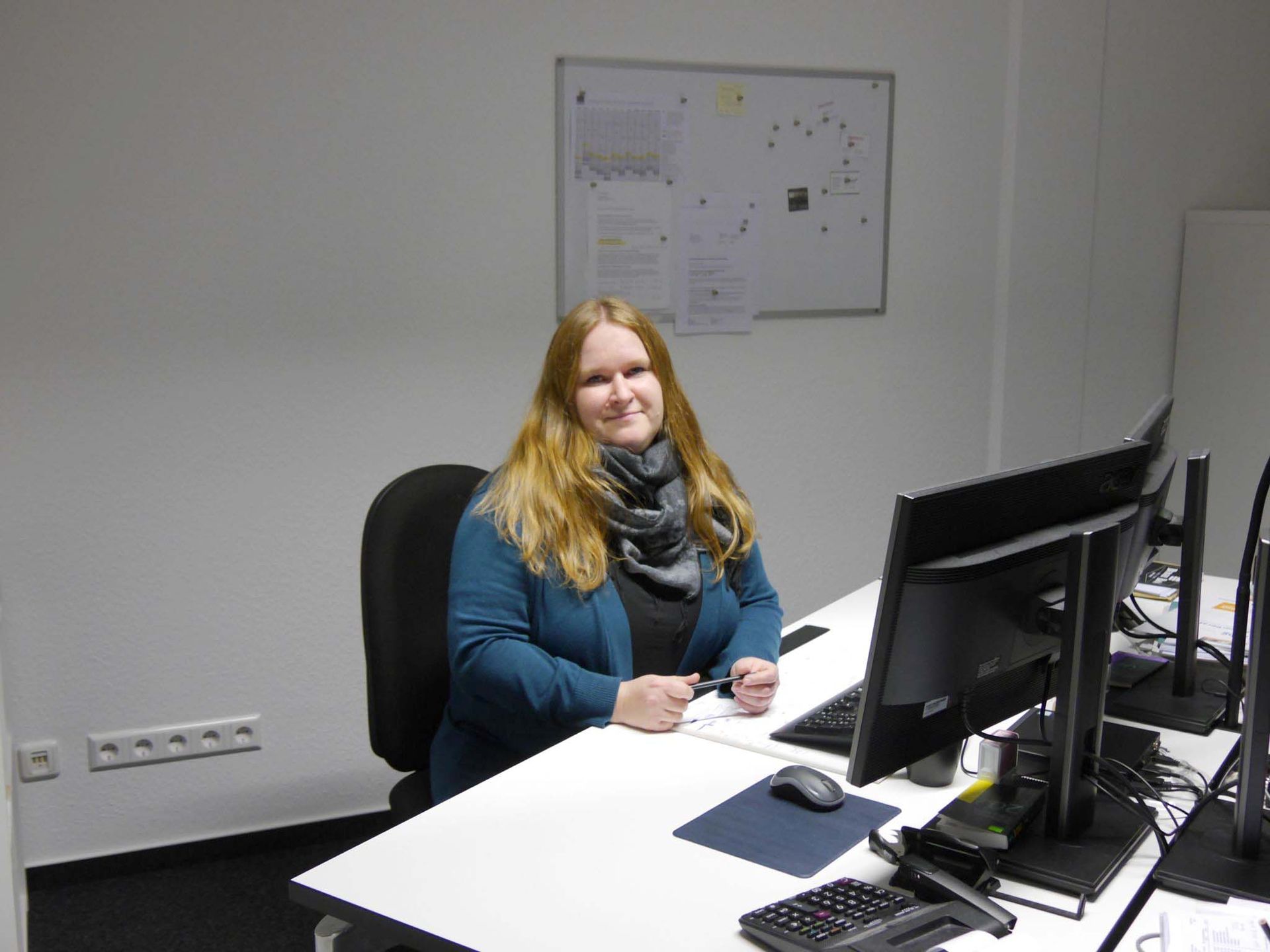 Eine Frau sitzt an einem Schreibtisch vor einem Computer.