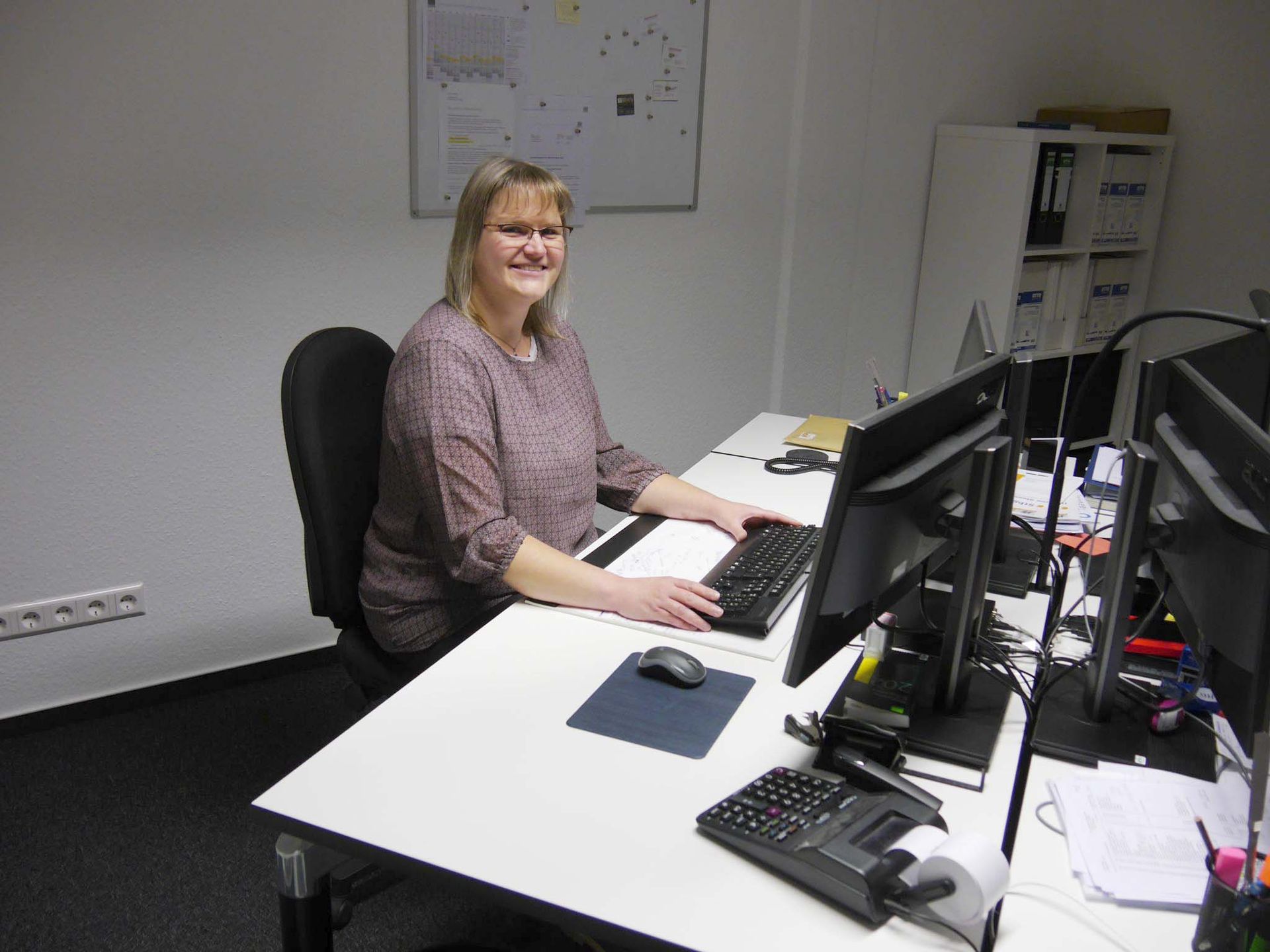 Eine Frau sitzt an einem Schreibtisch und benutzt einen Computer