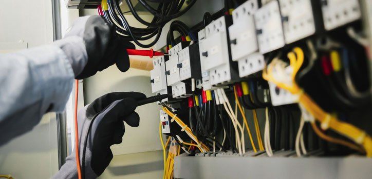Electrical engineers test electrical installations and wiring on protective relays, measuring them with a multimeter