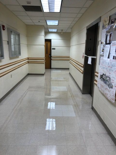 A long hallway with a bulletin board on the wall