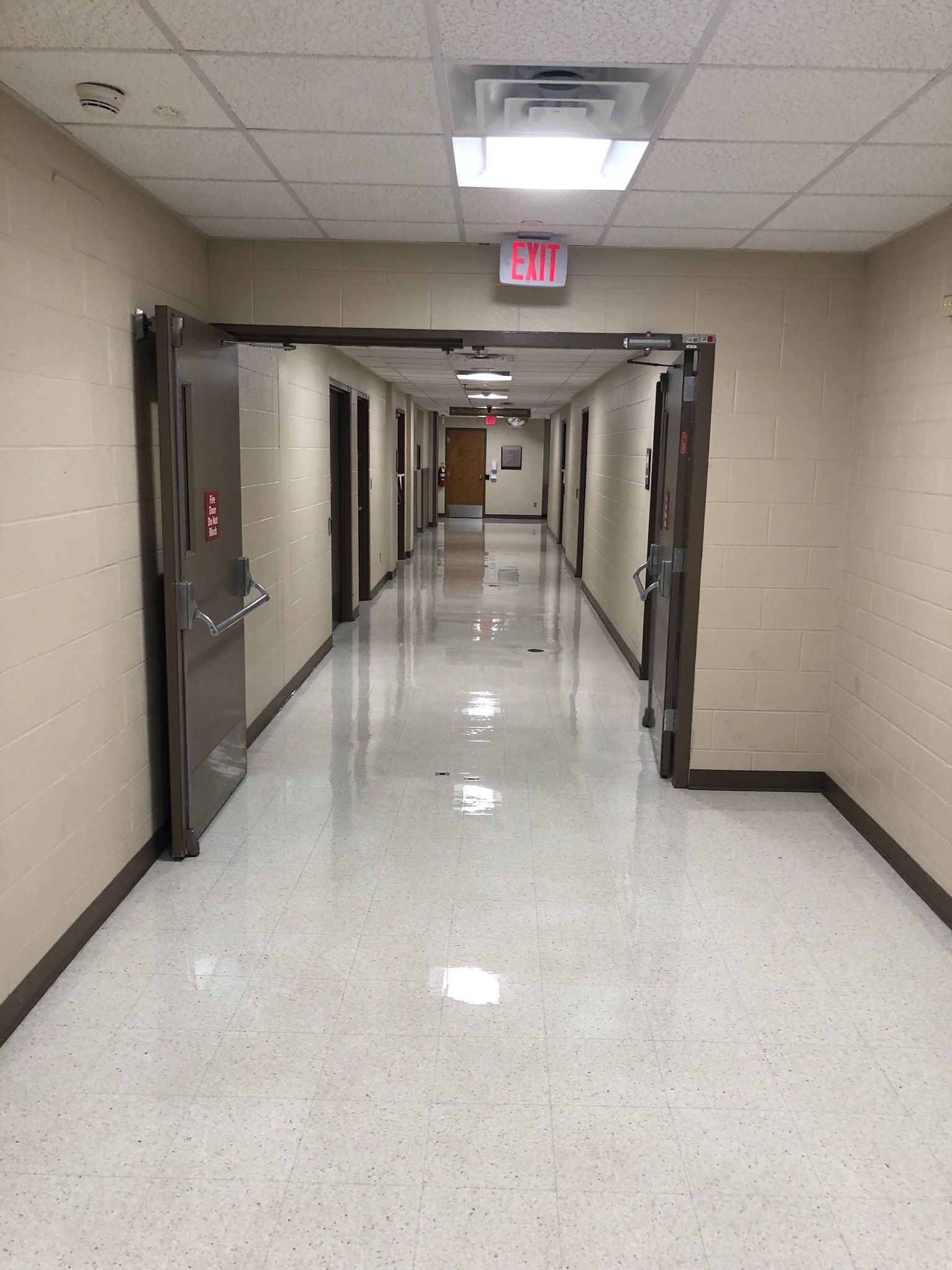 Hallway with doors on each side, leading to an exit sign at the end.