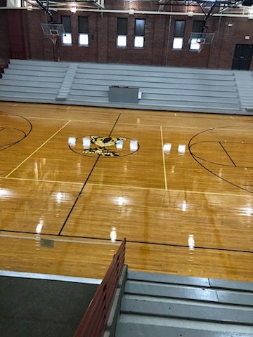 A basketball court in a gym with stairs leading up to it.