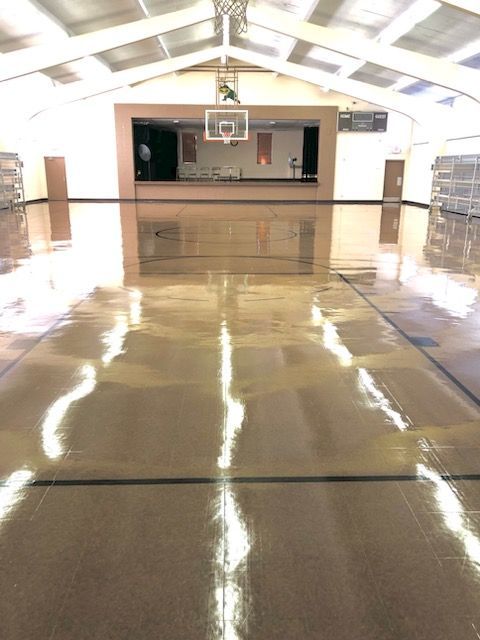 An empty gym with a basketball hoop in the middle