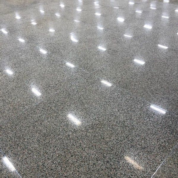 A close up of a shiny concrete floor with a lot of lights reflecting off of it.
