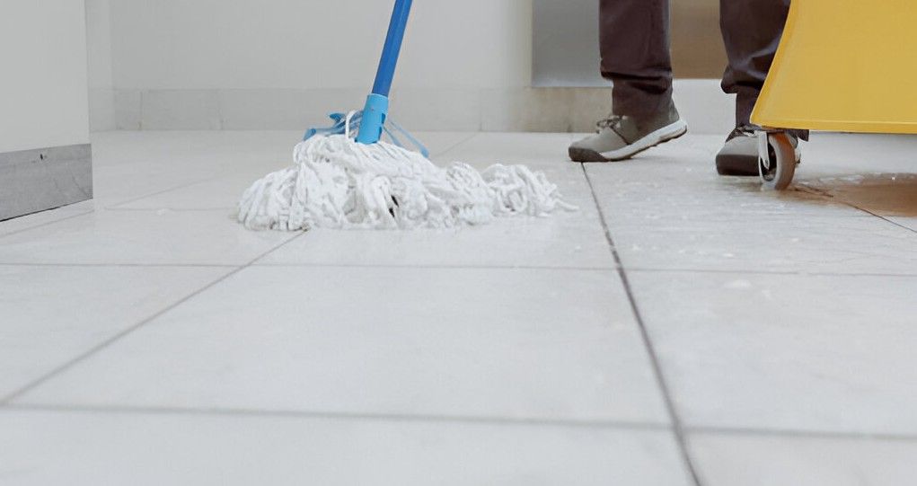 A person is mopping a tiled floor with a mop.