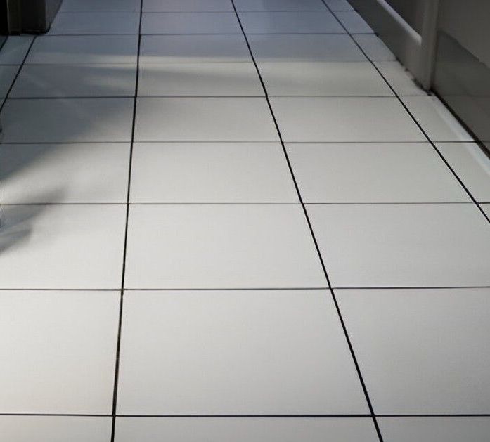 A man is cleaning a bathroom floor with a vacuum cleaner