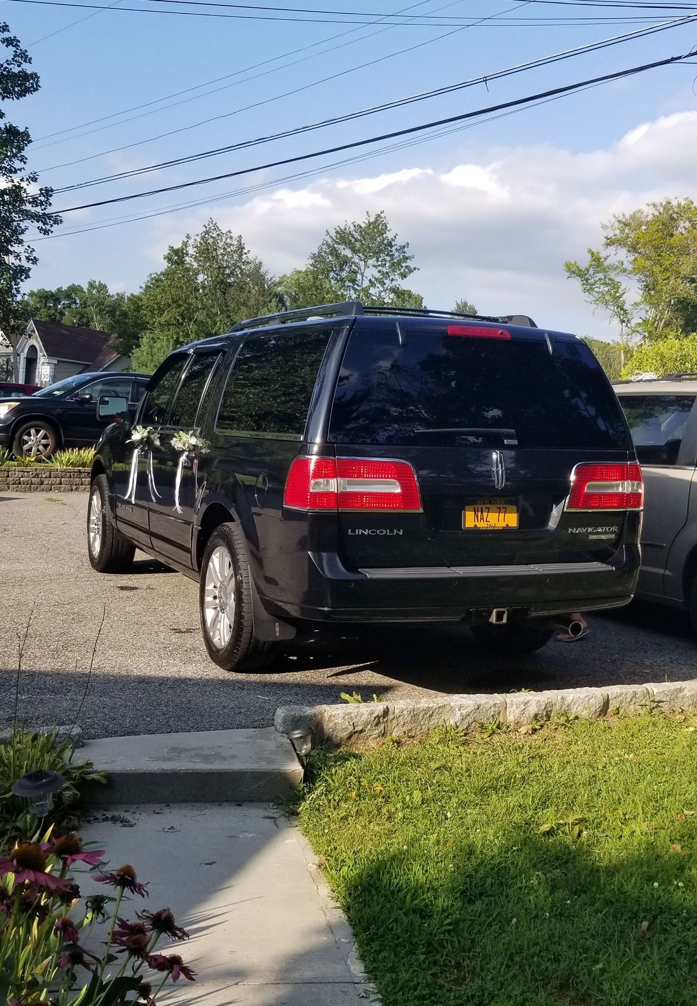 A black ford expedition is parked in a driveway next to a sidewalk.