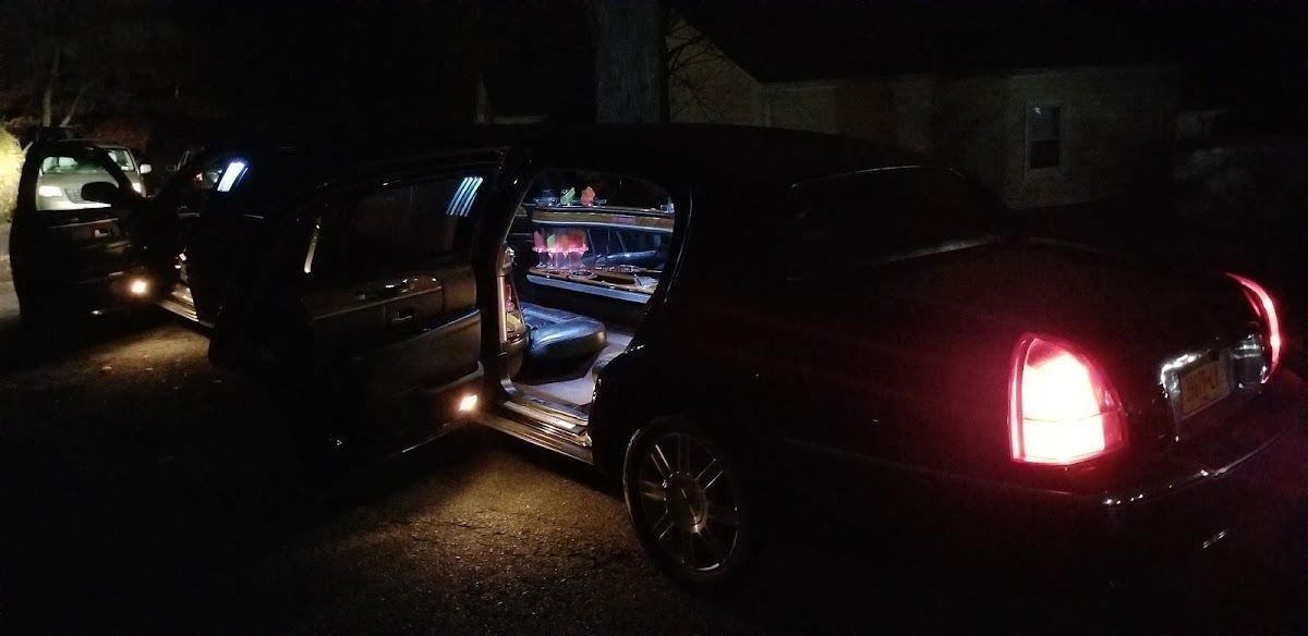Two cars are parked next to each other in a dark parking lot.