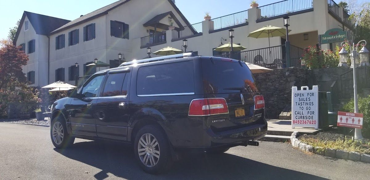 A black suv is parked in front of a large house.
