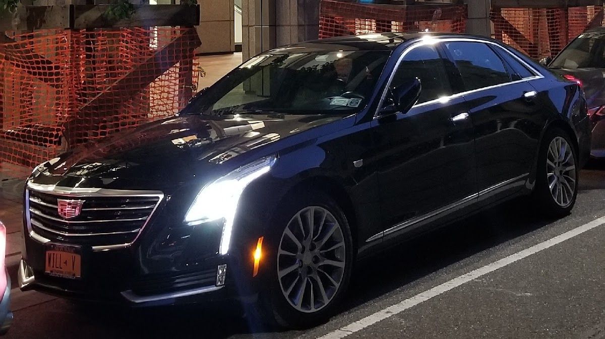 A black cadillac is parked on the side of the road