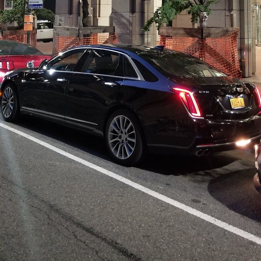 A black car with a new york license plate is parked on the side of the road