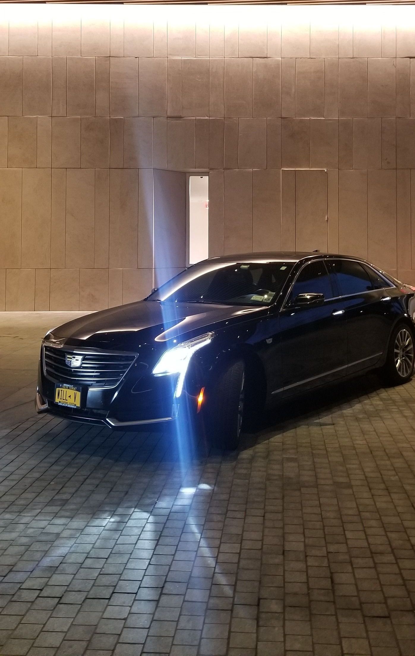 A black car is parked in a parking lot at night.