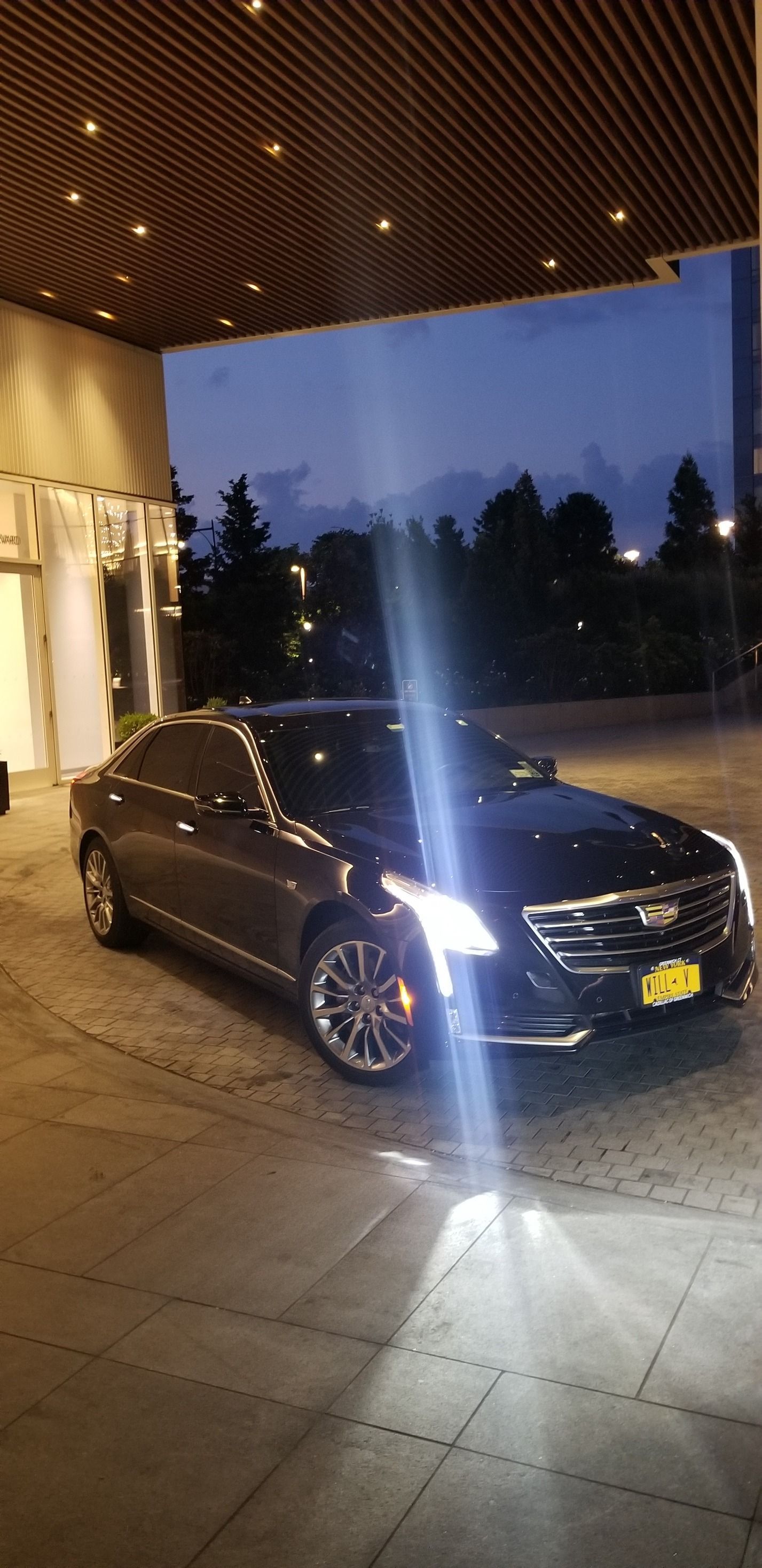 A black car is parked in front of a building at night.