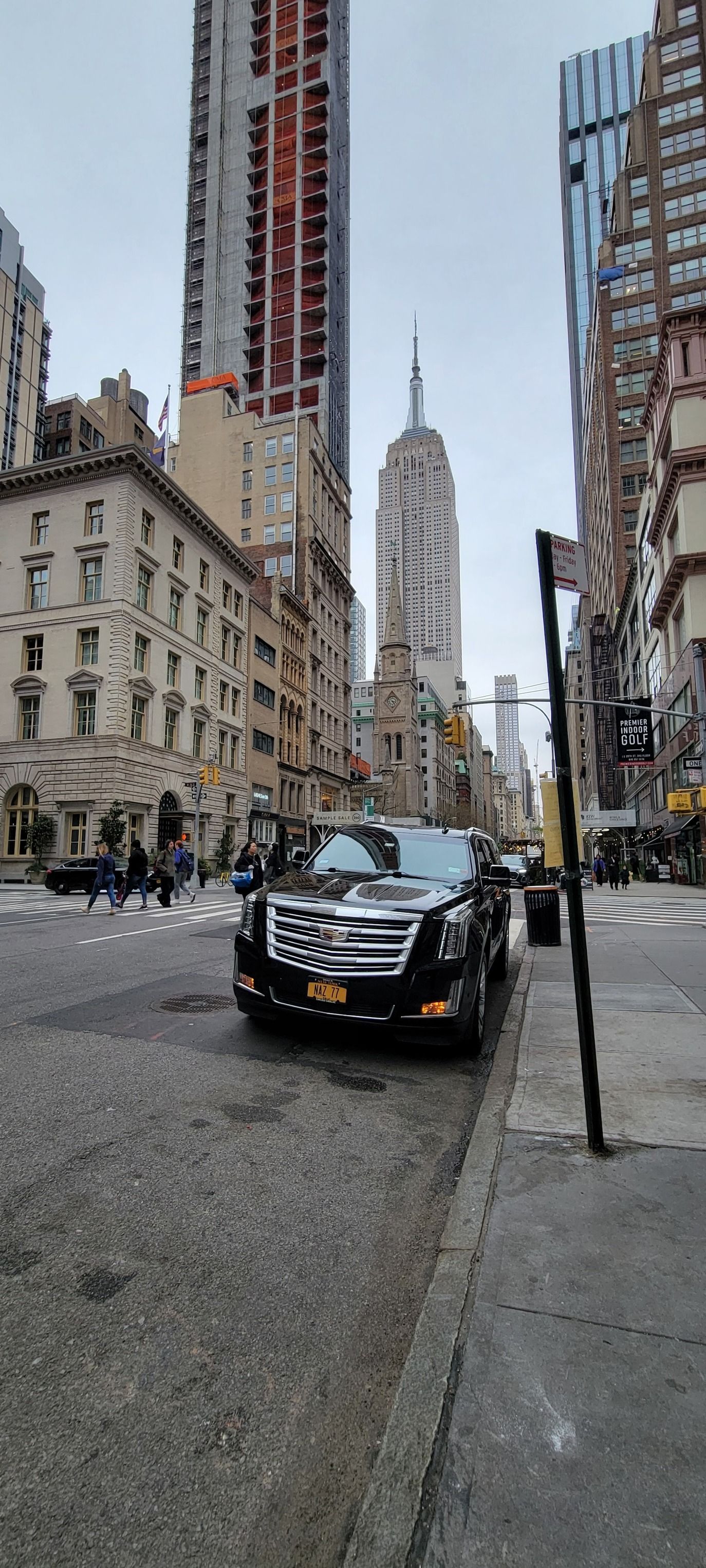 A black car is parked on the side of a city street.