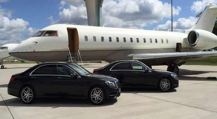 Two cars are parked in front of a private jet.