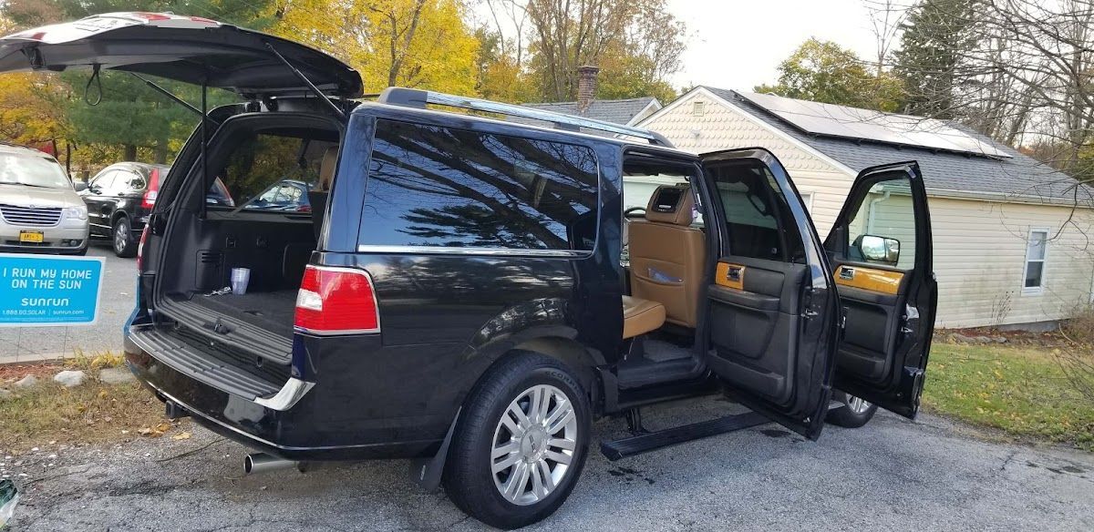 A black suv with its doors open is parked in front of a house.