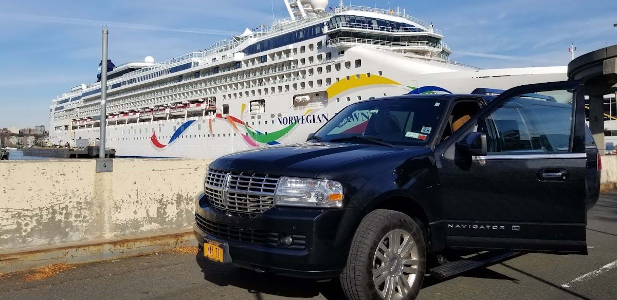 A black suv is parked in front of a large cruise ship.