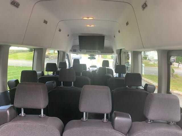 The inside of a van with lots of seats and a flat screen tv.