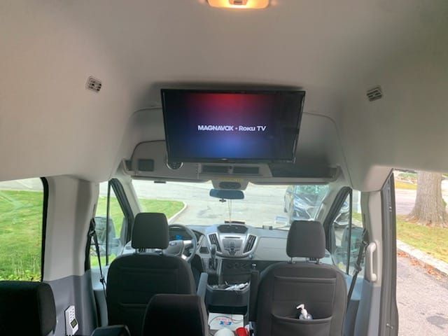 The inside of a van with a tv mounted to the ceiling.