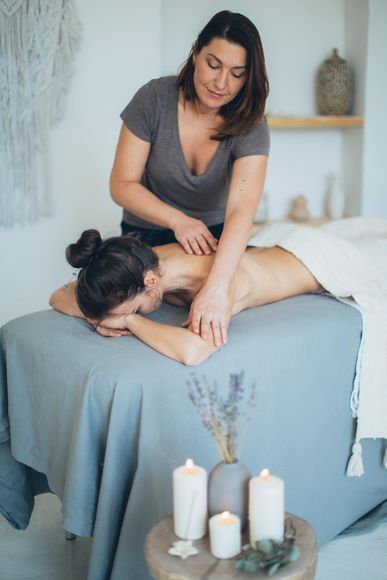 woman giving a woman massage in spa with candles lit, relaxing environment