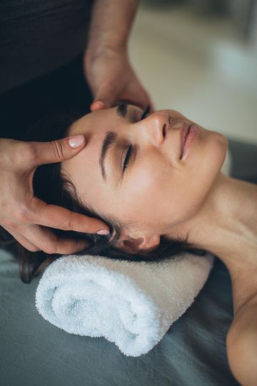 woman receiving facial and massage at spa