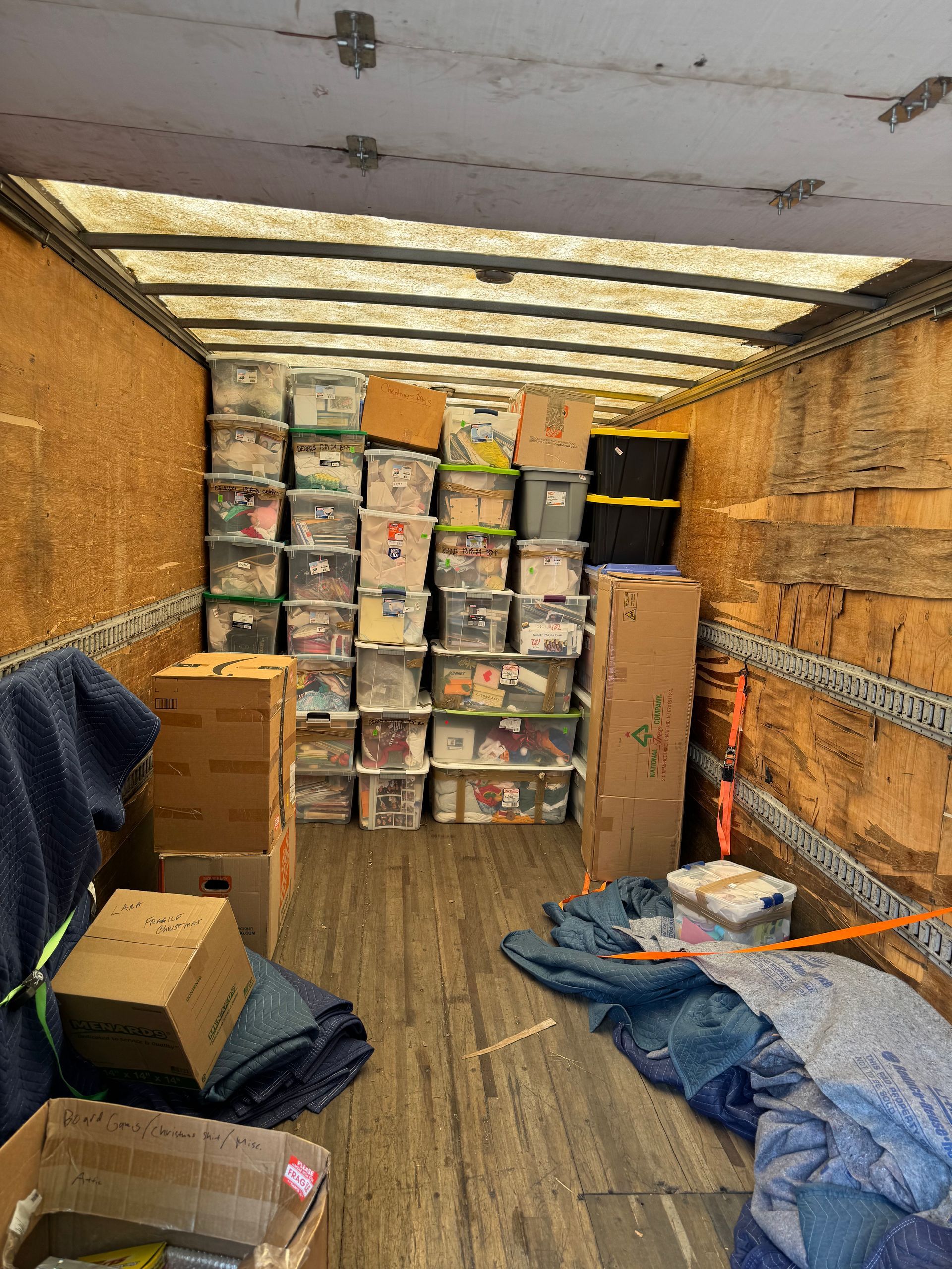 Inside a moving truck filled with stacked storage bins and boxes.