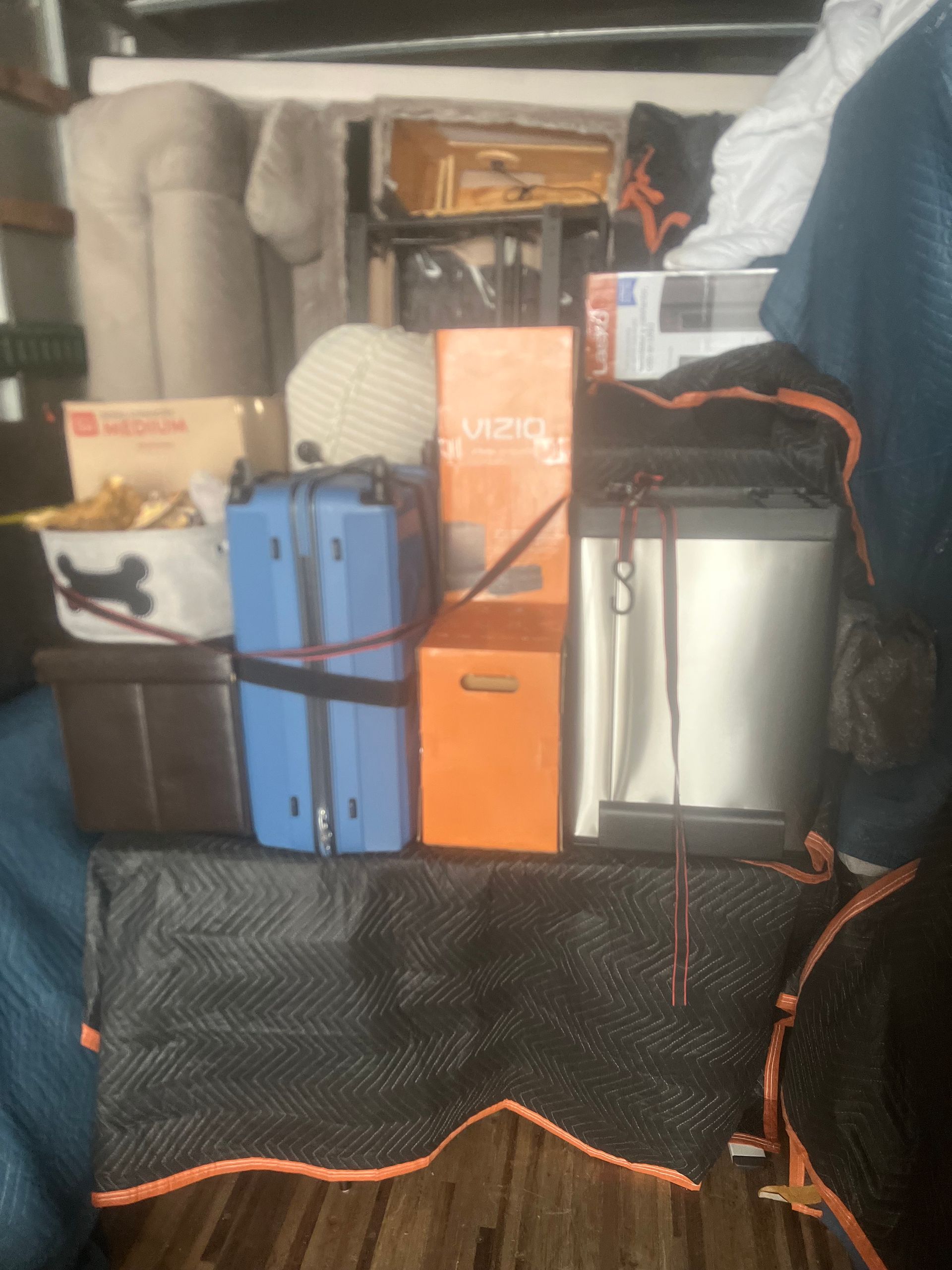 Boxes and luggage, mostly packed inside a moving truck.