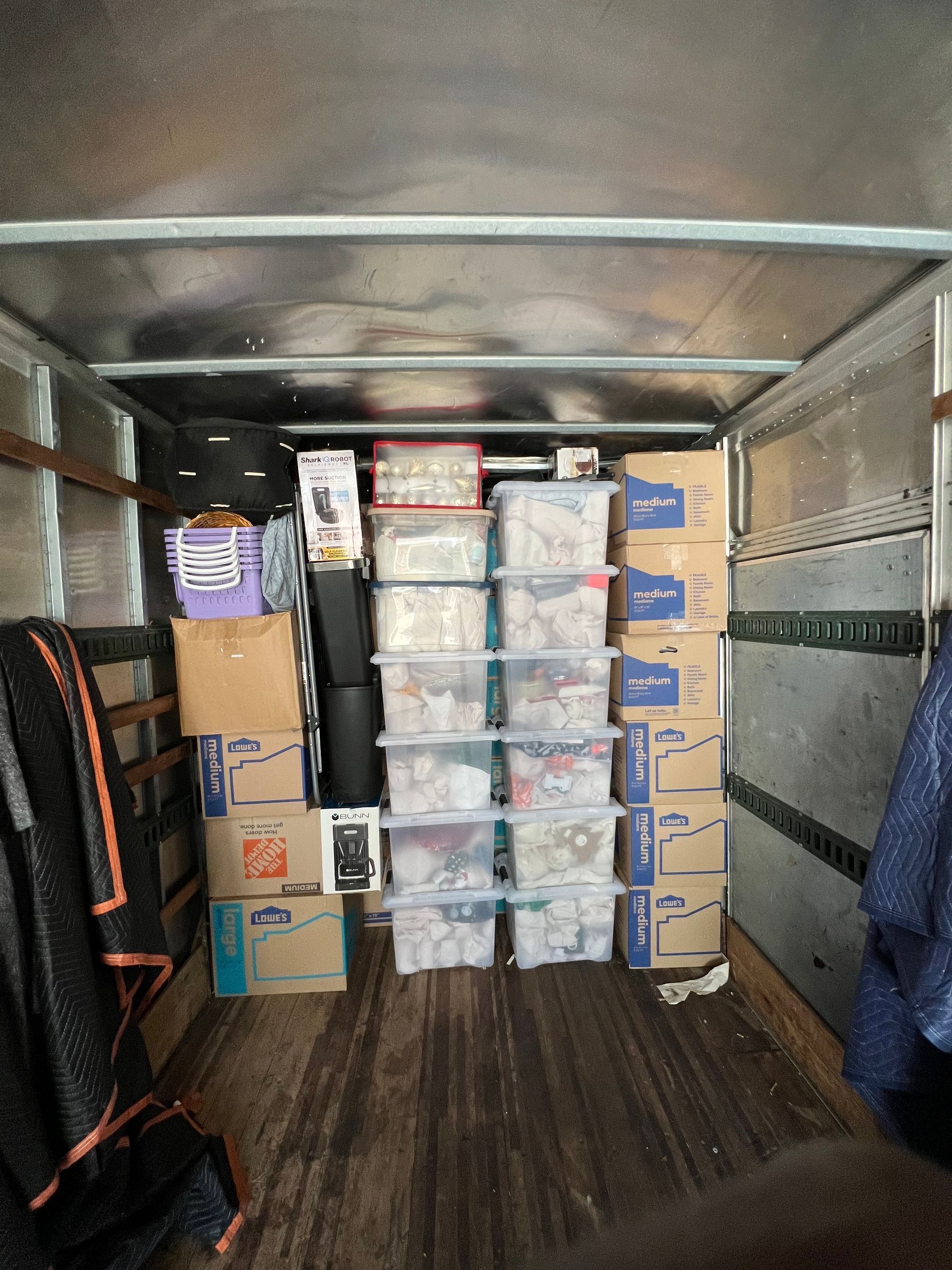A truck interior packed with boxes, bins, and household items for moving.