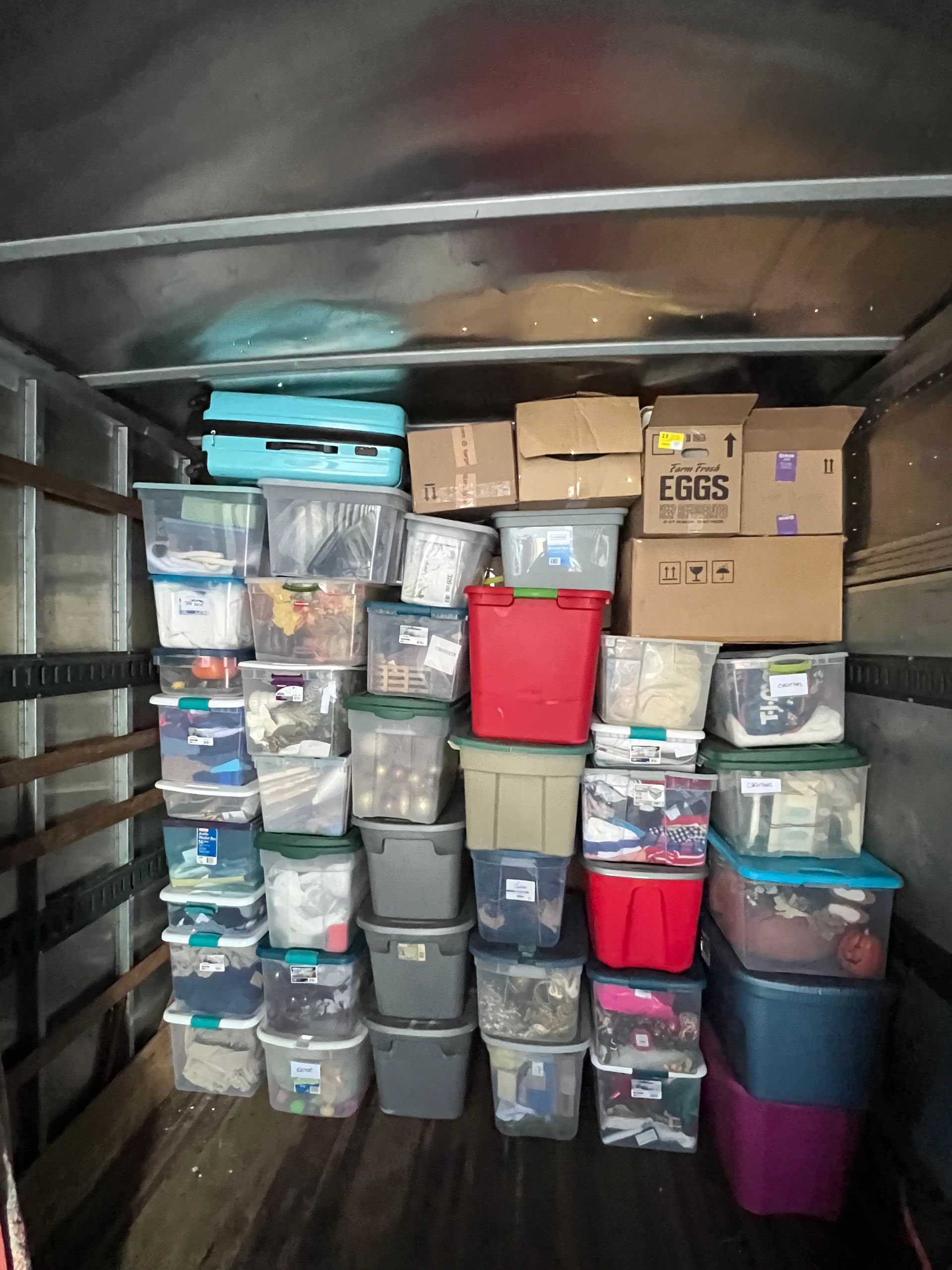 Boxes and bins stacked in a truck bed, containing various items for moving.