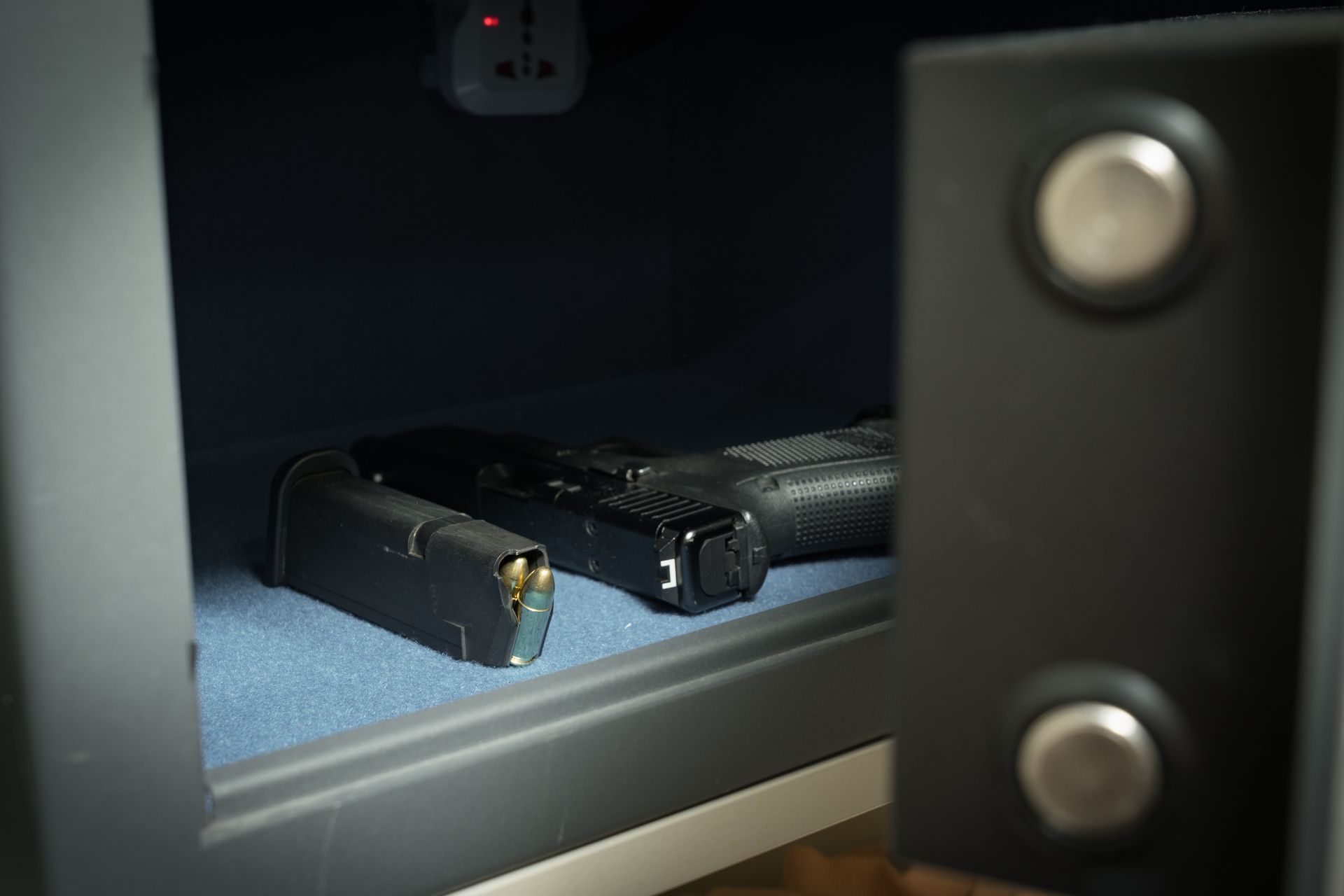 Open safe with a handgun and magazine inside.