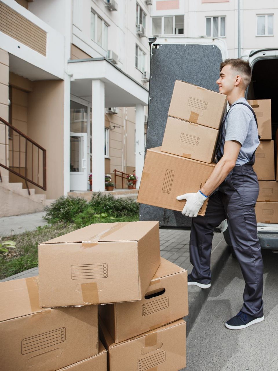 Moving worker carrying boxes to a truck outside an apartment building.