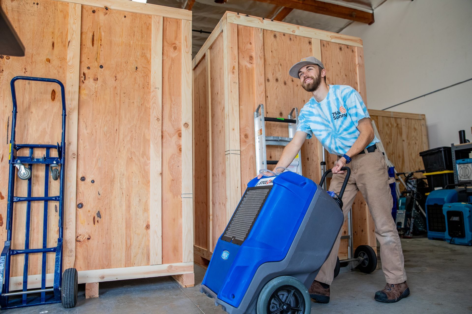 A man is pushing a blue cart in a warehouse
