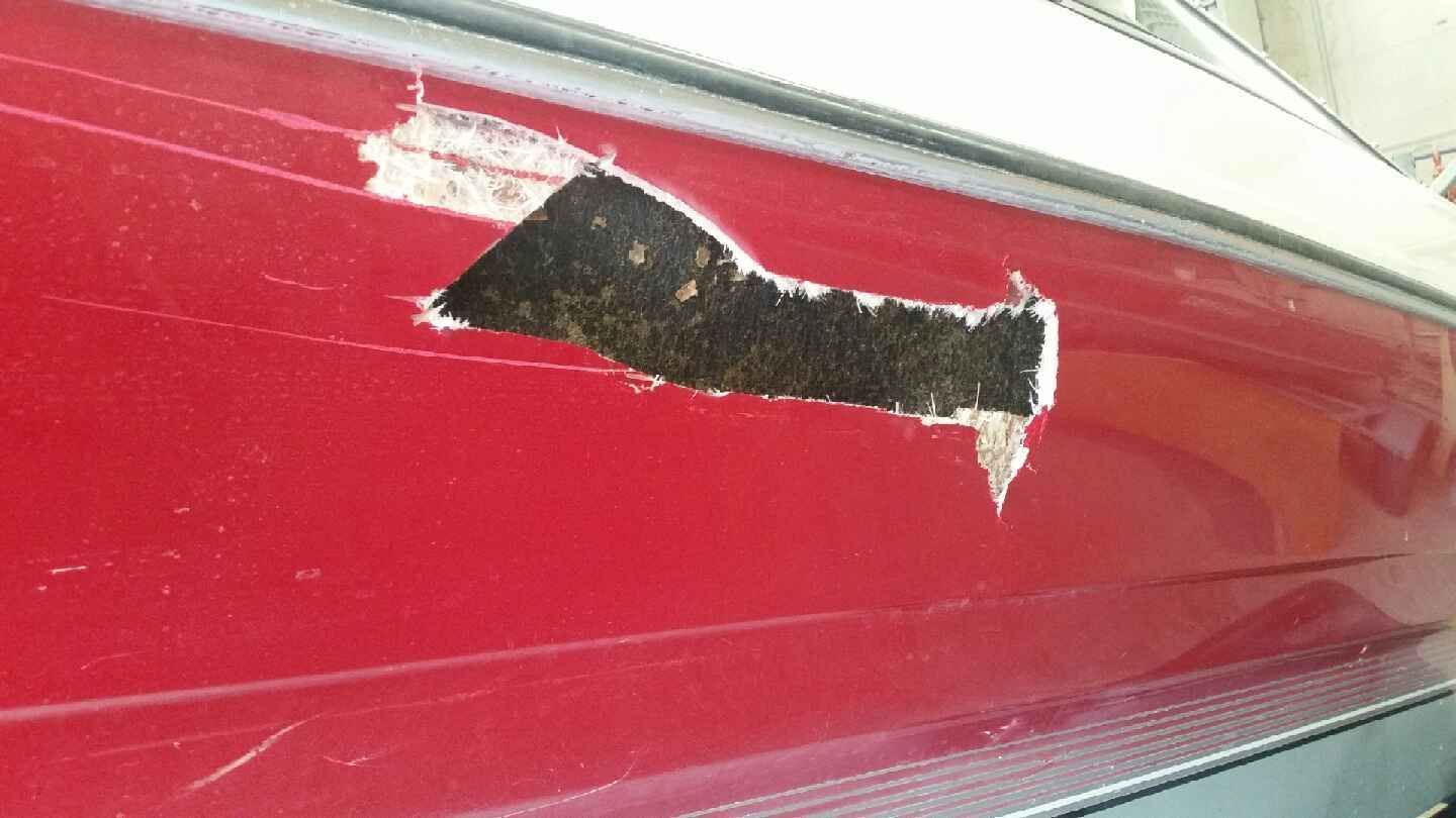 There is a hole in the side of a red boat.