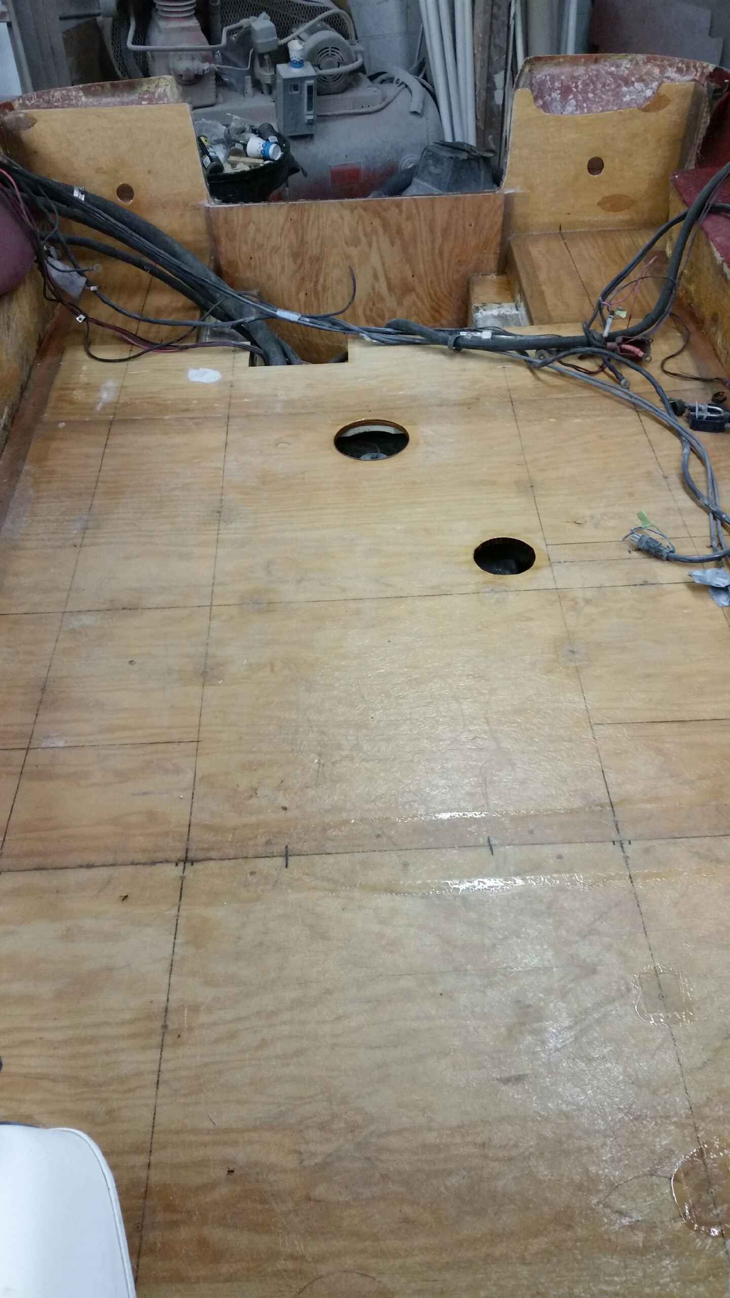 A wooden floor with holes in it and wires coming out of it.