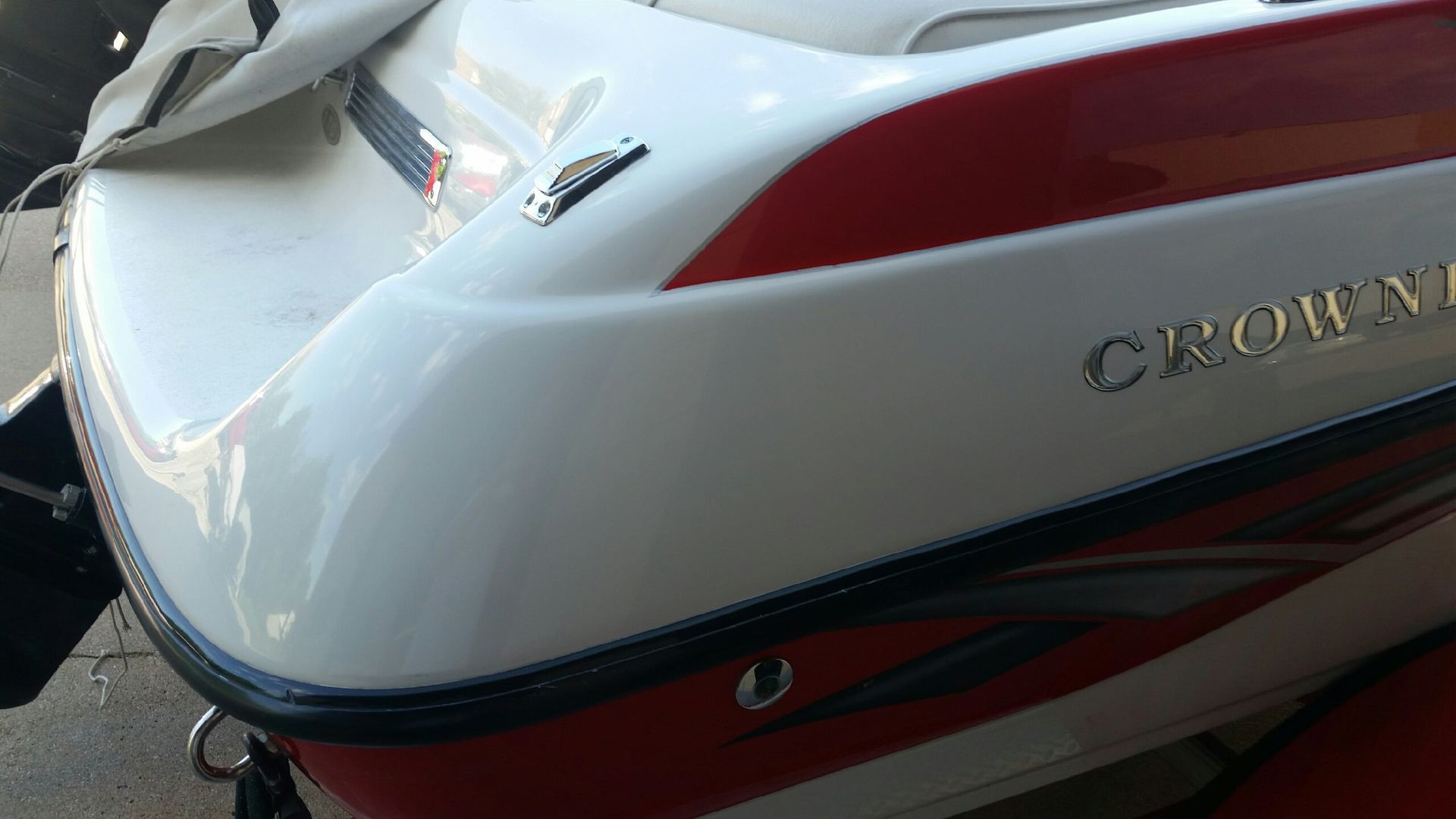 A red and white boat with the word crown on the side is parked on the ground.